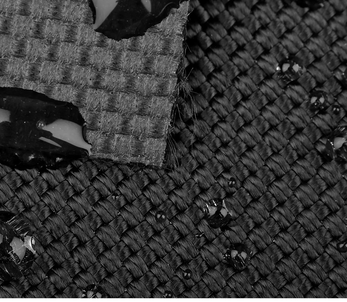 Close-up photograph of black ballistic fabric showing the interlaced yarns