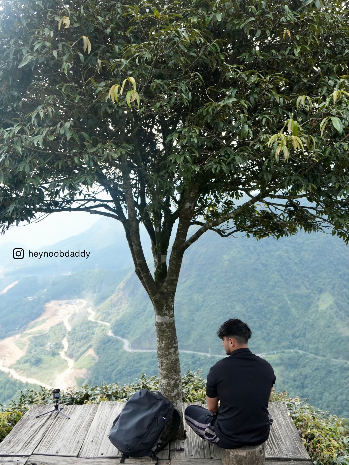 A person taking a quiet break beside their bag at a mountain lookout